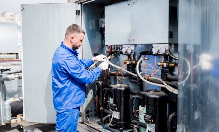 Technician servicing a large HVAC system and its refrigerant lines