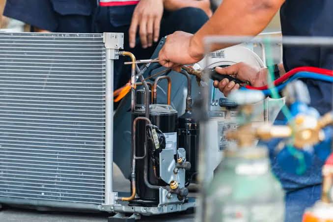 Hands repairing internal components of an air conditioning system