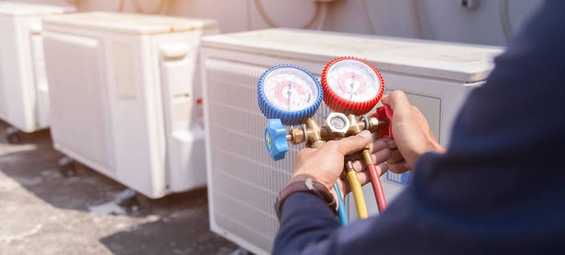 HVAC technician monitoring refrigerant pressure gauges