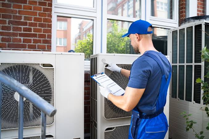 HVAC technician inspecting outdoor cooling equipment with a checklist